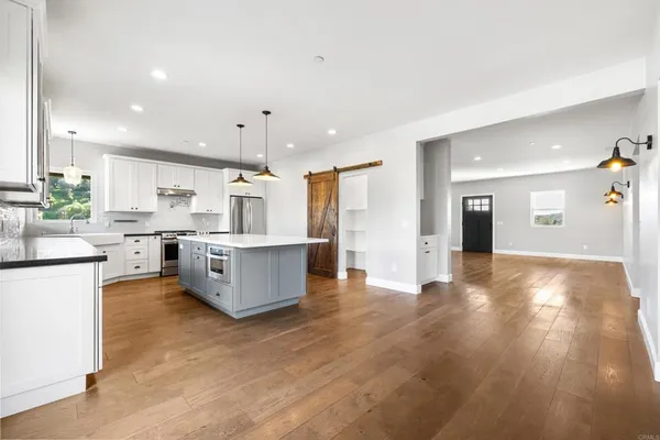a large kitchen with cabinets wooden floor and stainless steel appliances