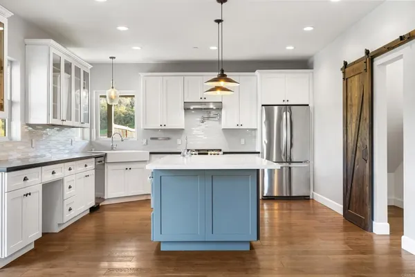 a kitchen with kitchen island granite countertop a sink appliances cabinets and wooden floor