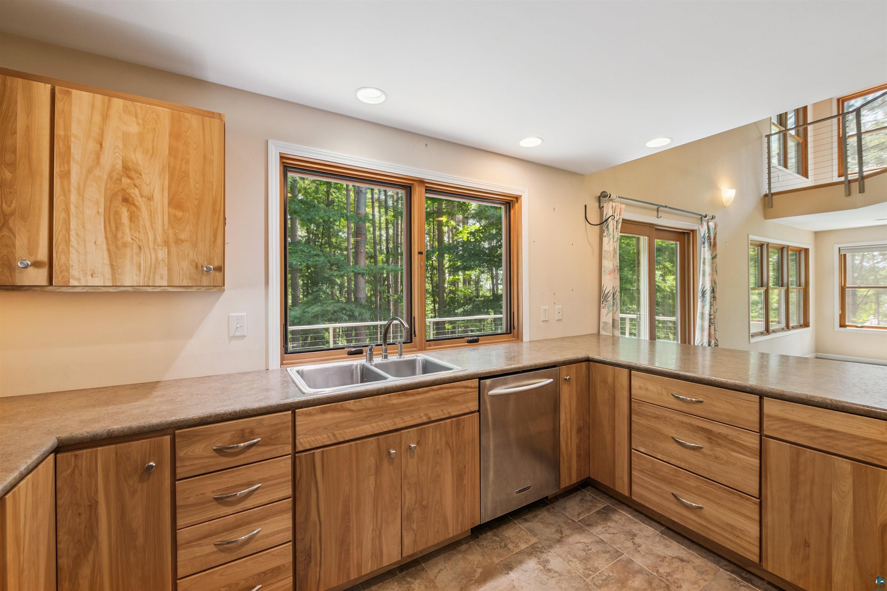 720 Rice Avenue Bayfield, WI 54814 - Photo 15 of 47 Kitchen featuring stainless steel dishwasher, recessed lighting, brown cabinetry, and light countertops