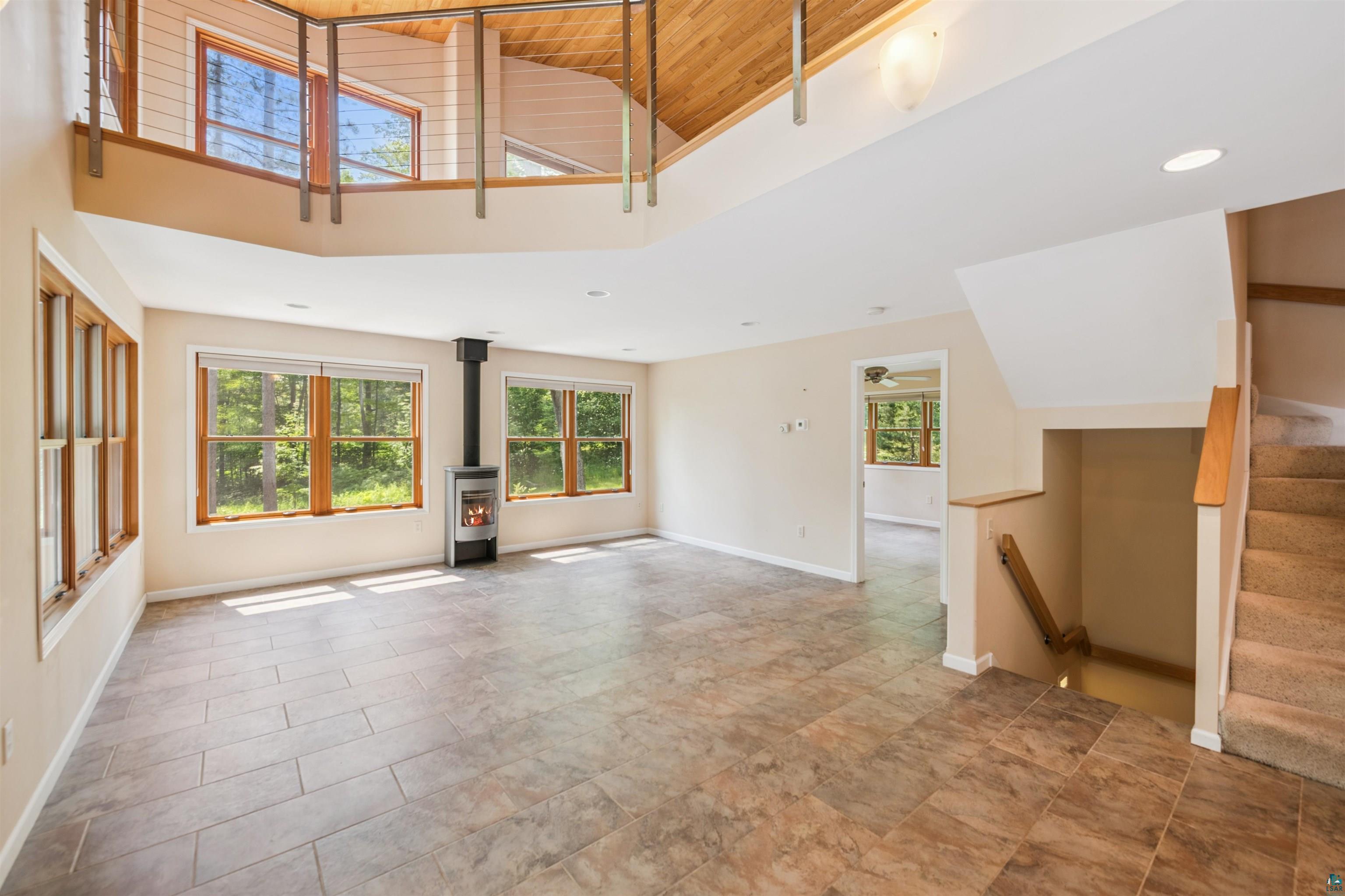 720 Rice Avenue Bayfield, WI 54814 - Photo 10 of 47 Unfurnished living room with a wood stove, wood ceiling, high vaulted ceiling, stairway, and recessed lighting