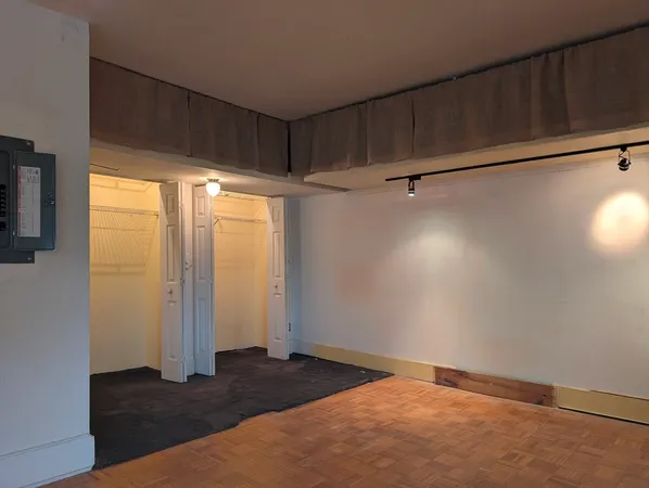 a view of an empty room with wooden floor and a window