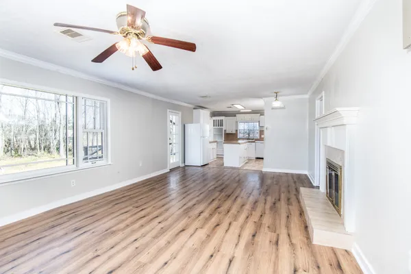 a view of a livingroom with wooden floor a ceiling fan and windows