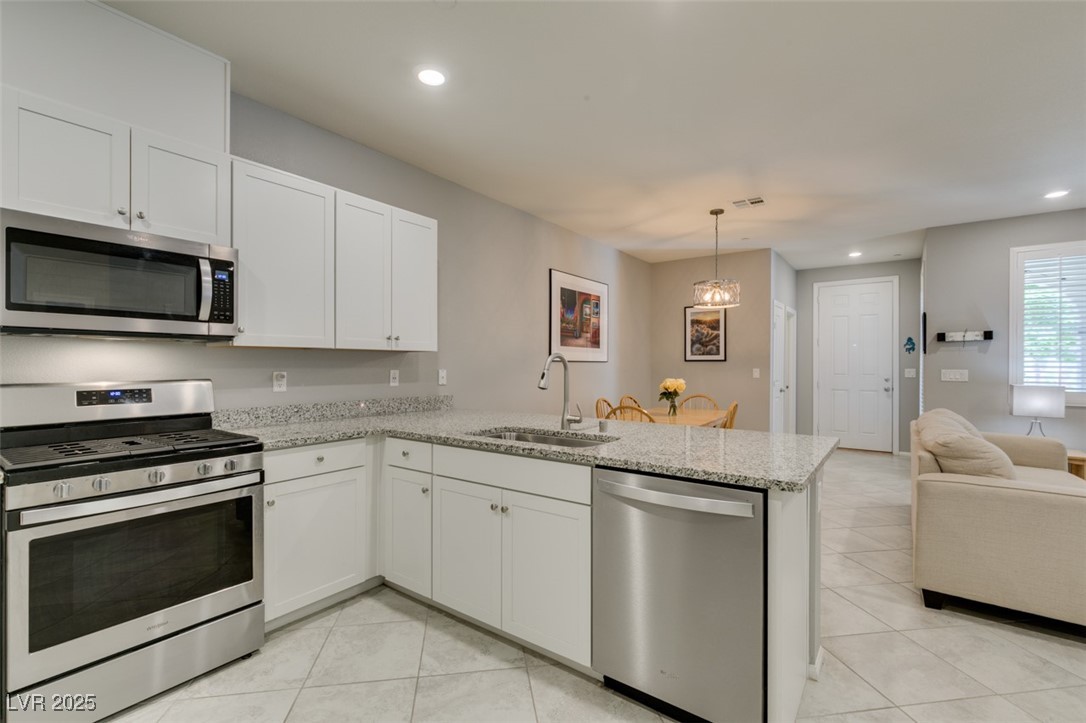 2870 Turnstone Ridge Street Henderson, NV 89044 - Photo 25 of 50 Kitchen with appliances with stainless steel finishes, a sink, a peninsula, light tile patterned flooring, and recessed lighting