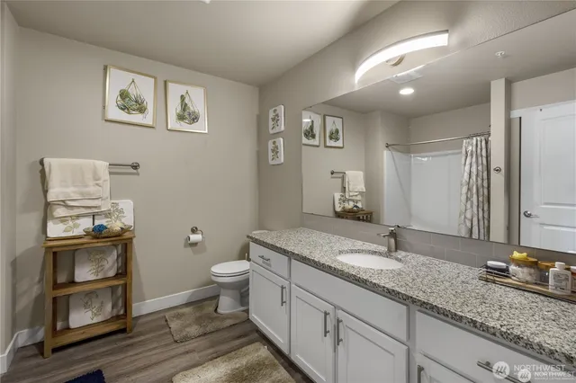 a bathroom with a granite countertop sink a toilet and a mirror