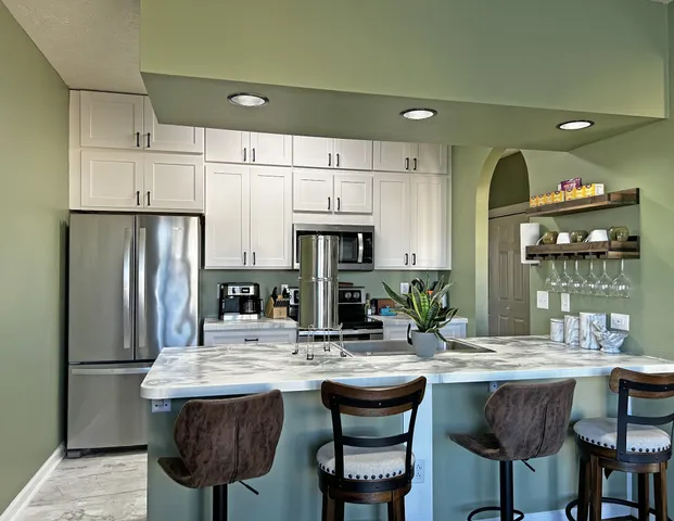 a kitchen with stainless steel appliances granite countertop a kitchen island a table and chairs