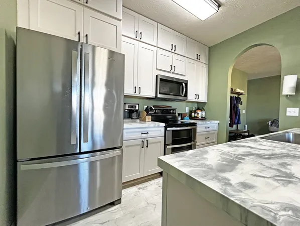 a kitchen with granite countertop a refrigerator stove and microwave