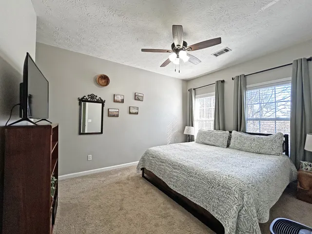 a bedroom with a large bed and a flat tv screen on dresser