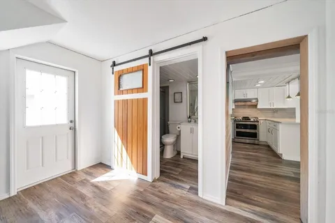 a view of a hallway with wooden floor and a bathroom