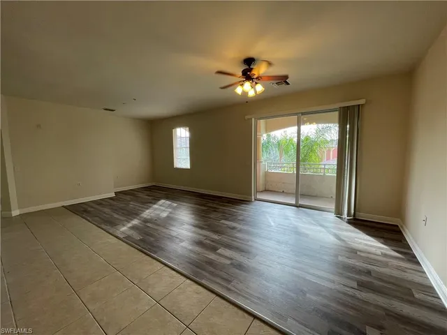 a view of empty room with wooden floor and fan