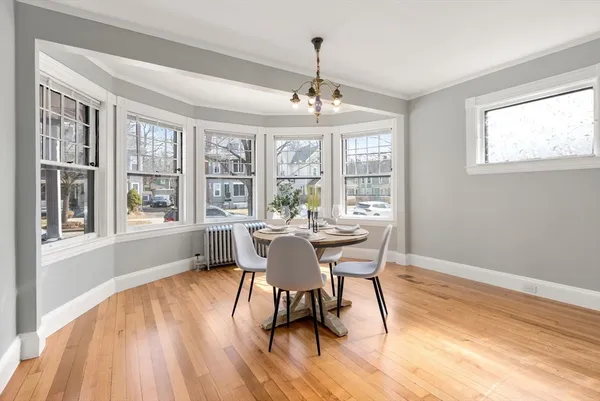 a dining room with wooden floor a chandelier a glass table and chairs