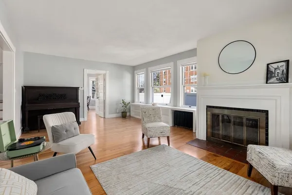 a living room with furniture a fireplace a rug and a window