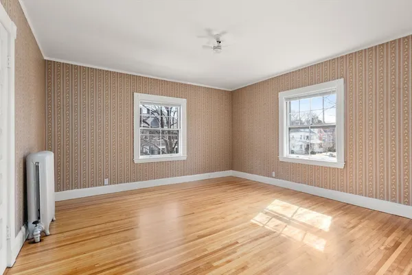a view of empty room with wooden floor and fan