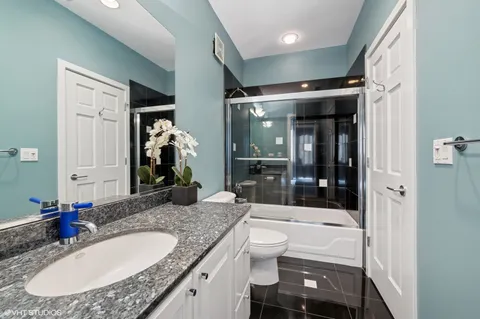a bathroom with a granite countertop sink a toilet a mirror and shower