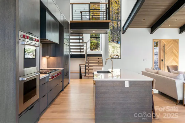 a living room with stainless steel appliances wooden floors and a large window