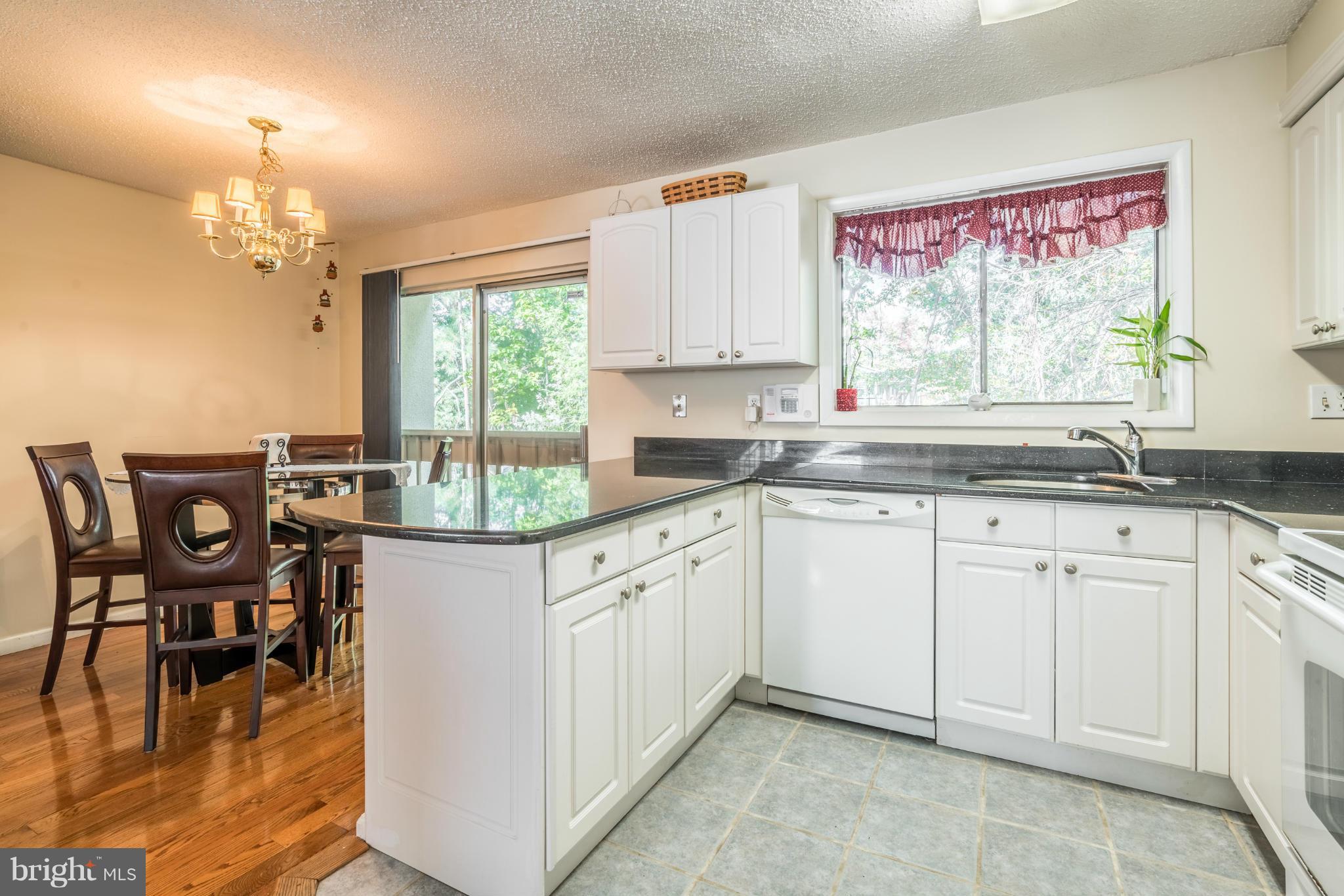 2402 Southgate Square Reston, VA 20191 - Photo 8 of 21 a kitchen with granite countertop white cabinets dining table and chairs
