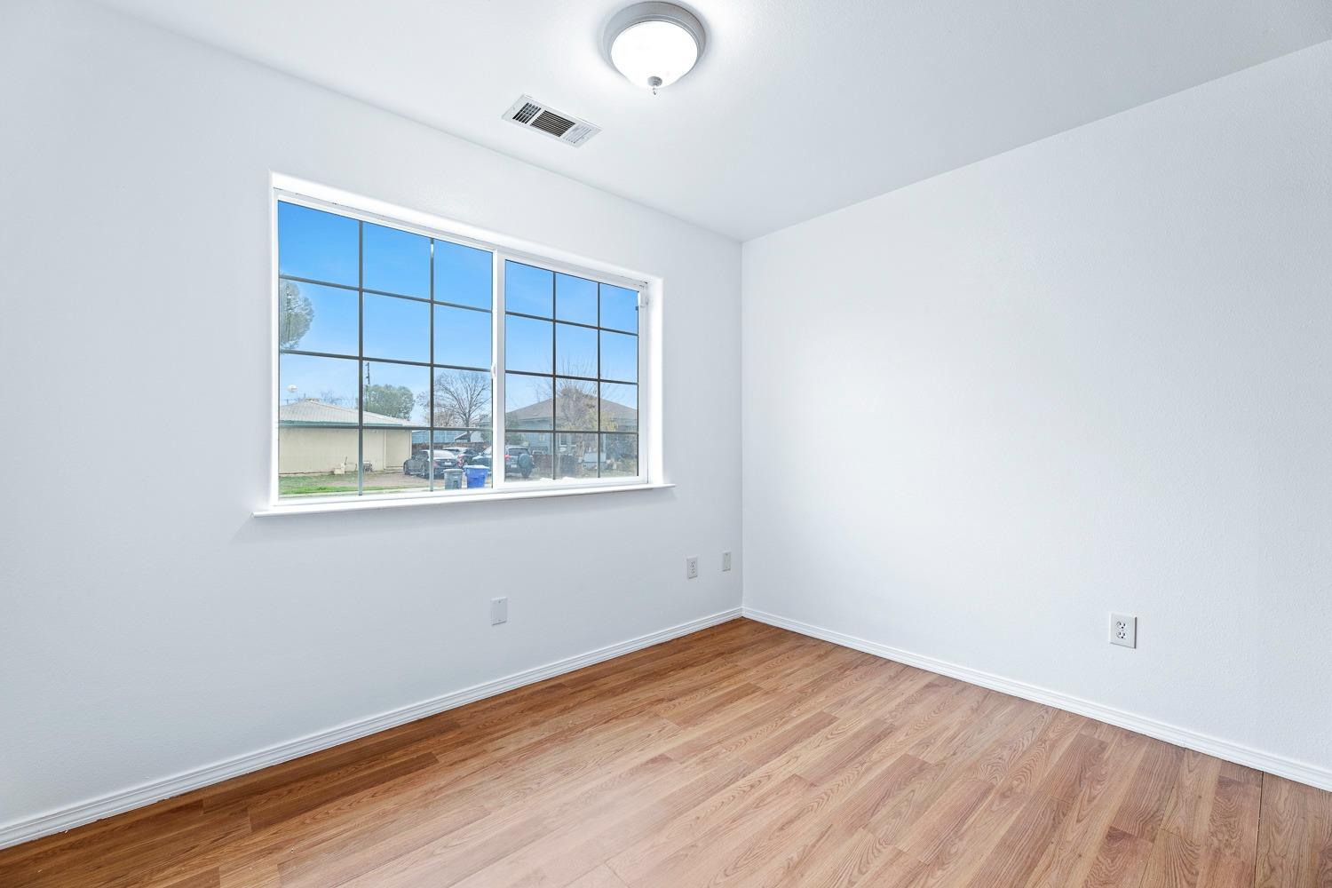 249 Jackson Street Coalinga, CA 93210 - Photo 11 of 42 an empty room with wooden floor and windows