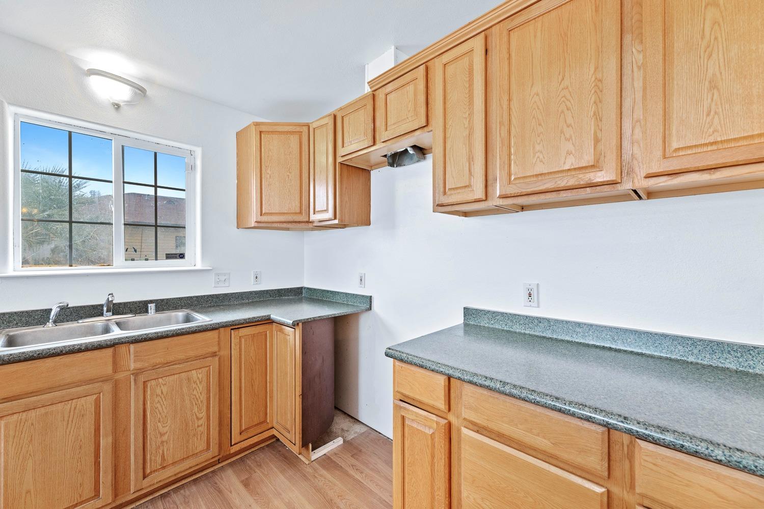 249 Jackson Street Coalinga, CA 93210 - Photo 15 of 42 a kitchen with stainless steel appliances granite countertop a sink and cabinets with wooden floor
