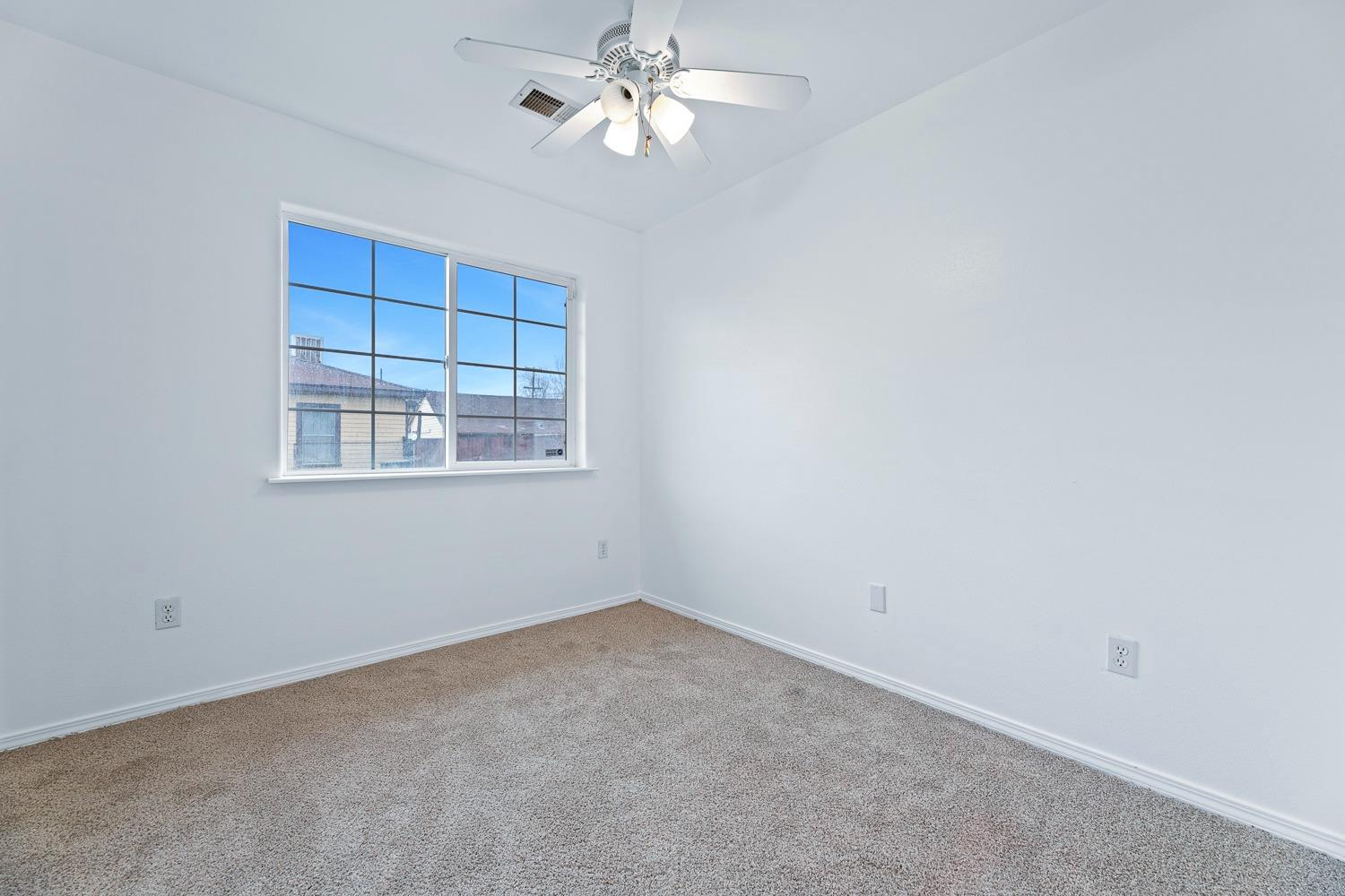249 Jackson Street Coalinga, CA 93210 - Photo 19 of 42 an empty room with chandelier fan and windows