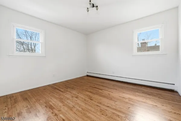 a view of an empty room with wooden floor and a ceiling fan
