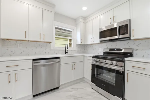 a kitchen with white cabinets and stainless steel appliances
