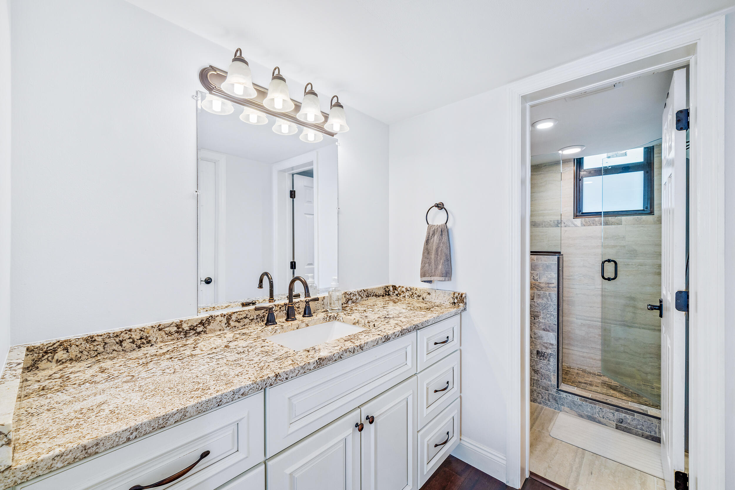 1648 Jupiter Cove Drive, Unit 514B Jupiter, FL 33469 - Photo 12 of 21 a bathroom with a granite countertop sink a mirror and a shower
