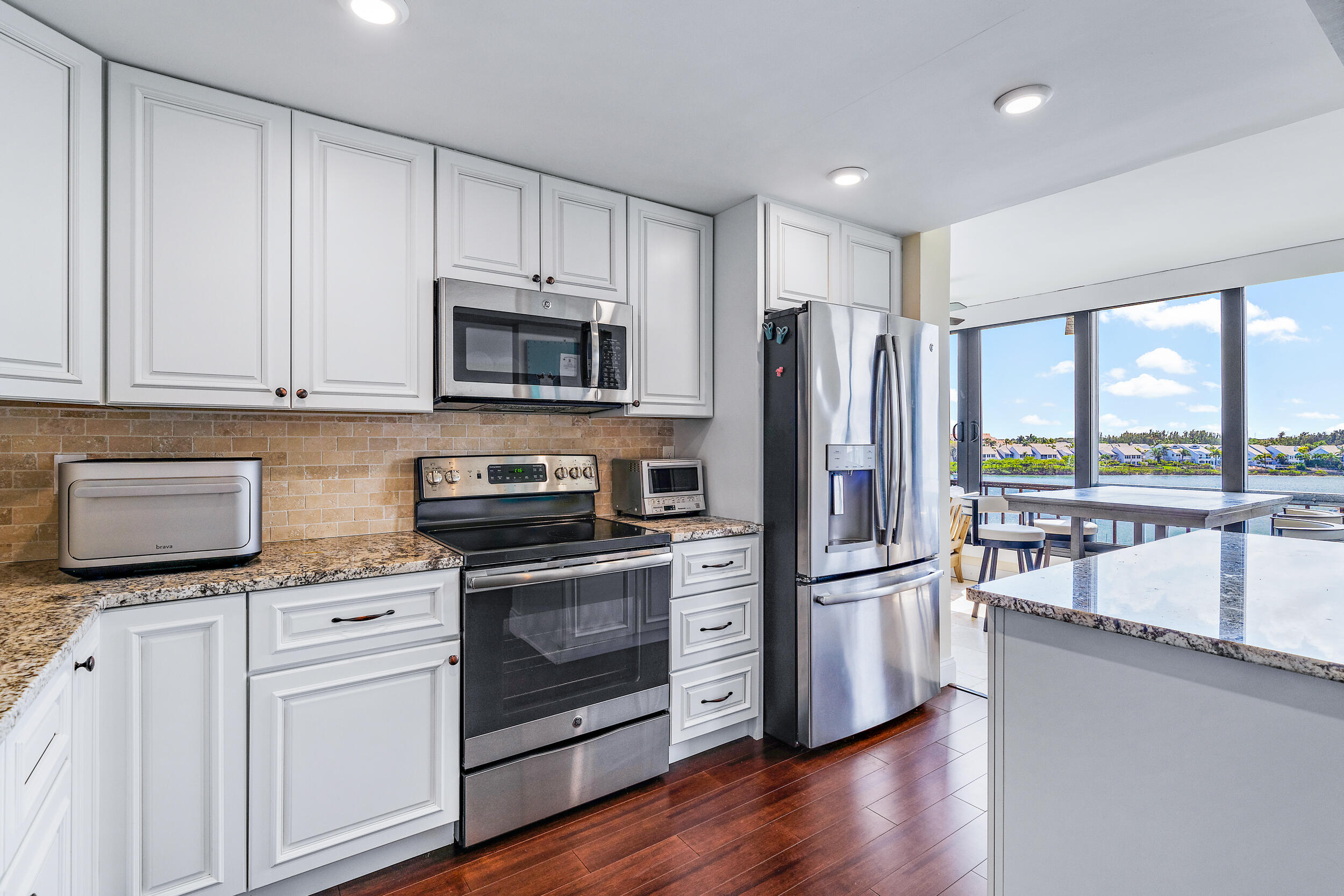 1648 Jupiter Cove Drive, Unit 514B Jupiter, FL 33469 - Photo 8 of 21 a kitchen with stainless steel appliances granite countertop a refrigerator microwave and stove top oven