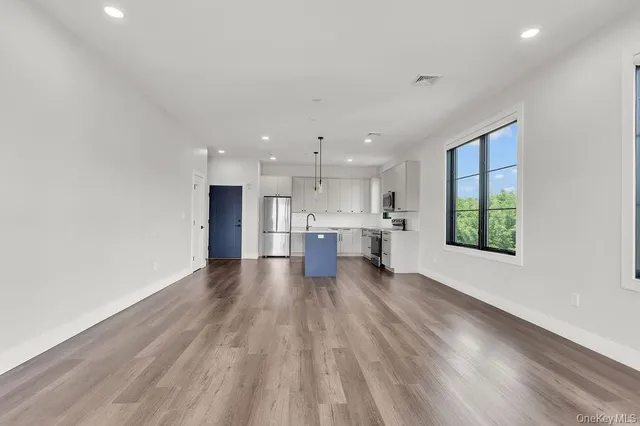 a view of kitchen with kitchen island wooden floors and stainless steel appliances