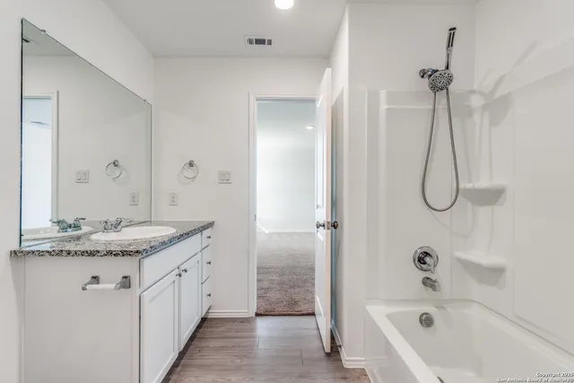 a bathroom with a granite countertop sink a mirror and a bathtub