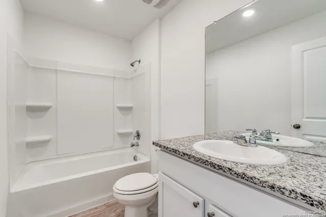 a bathroom with a granite countertop sink a toilet and bathtub