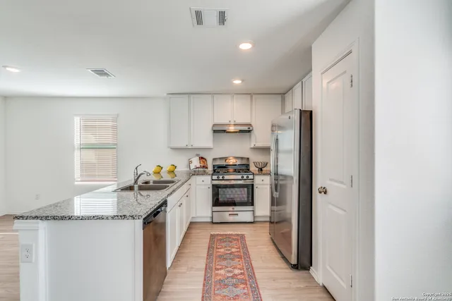 a kitchen with granite countertop a refrigerator stove and sink