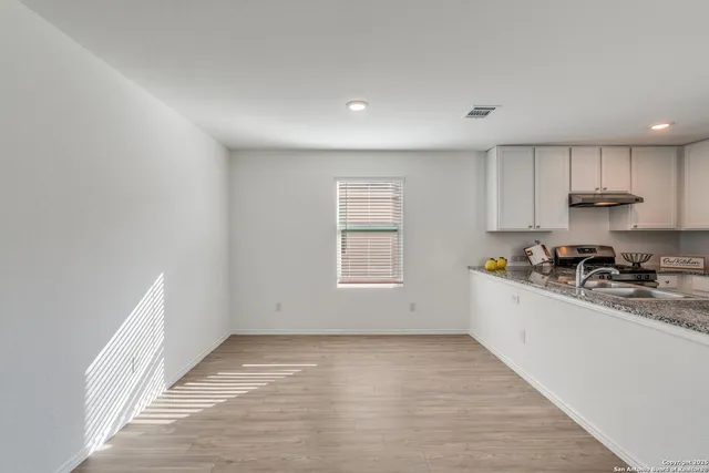 a view of a kitchen with a sink and dishwasher a stove top oven with white cabinets