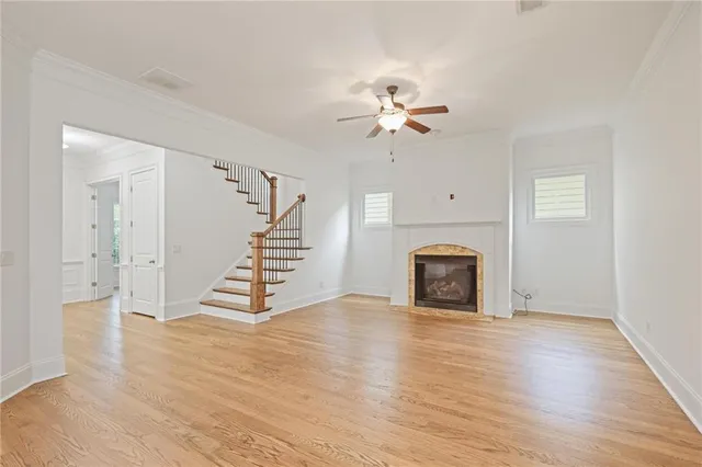 a view of an empty room with wooden floor and a fireplace