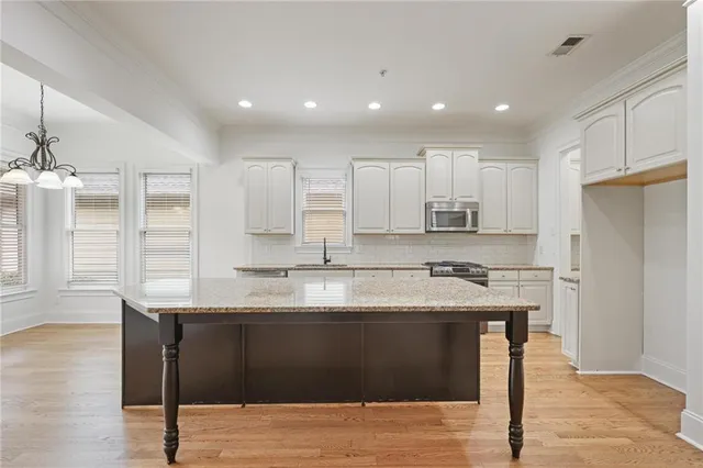 a kitchen with stainless steel appliances granite countertop a sink a stove a refrigerator and island with wooden floor