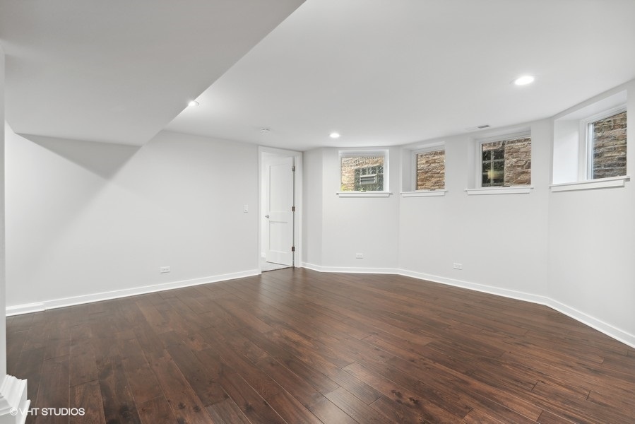 1220 West Roscoe Street Chicago, IL 60657 - Photo 15 of 35 a view of an empty room with wooden floor and a window