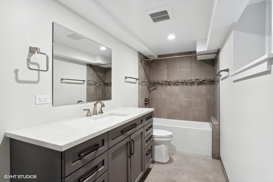 1220 West Roscoe Street Chicago, IL 60657 - Photo 18 of 35 a bathroom with a sink a toilet and a large mirror