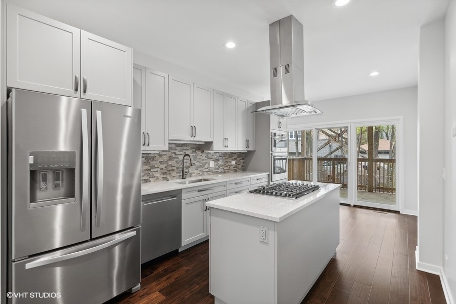 1220 West Roscoe Street Chicago, IL 60657 - Photo 6 of 35 a kitchen that has a refrigerator a stove and white cabinets with wooden floor