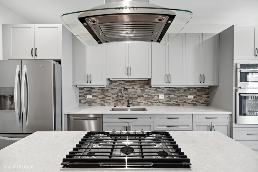 1220 West Roscoe Street Chicago, IL 60657 - Photo 7 of 35 a kitchen with kitchen island a stove a sink and cabinets