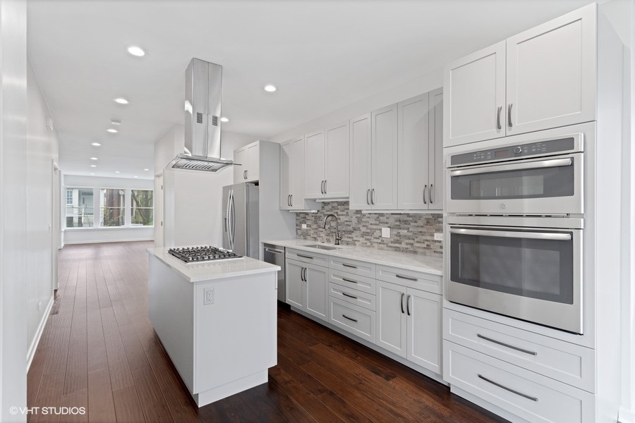1220 West Roscoe Street Chicago, IL 60657 - Photo 8 of 35 a kitchen with granite countertop white cabinets and white appliances
