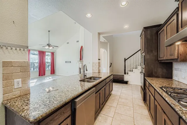 a large kitchen with stainless steel appliances kitchen island granite countertop a refrigerator and a sink