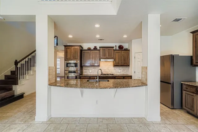 a kitchen with stainless steel appliances granite countertop a sink stove and cabinets