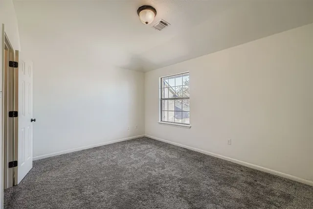 a view of an empty room with wooden floor and windows