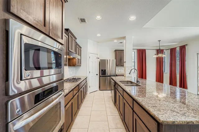 a kitchen with stainless steel appliances kitchen island granite countertop a stove and a sink