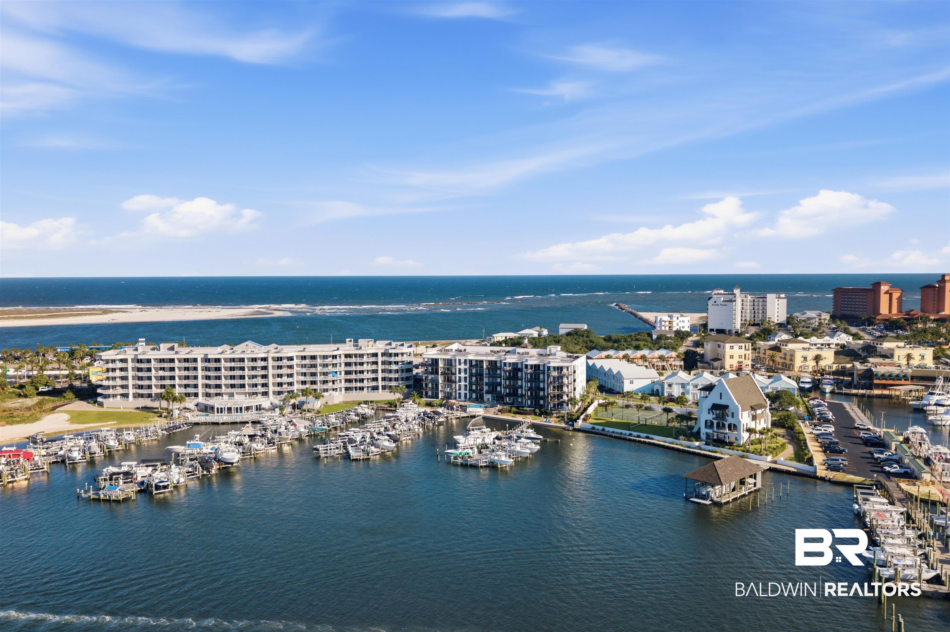 3564 Bayou Road, Unit 203 Orange Beach, AL 36561 - Photo 52 of 53 Coastal cityscape featuring a marina with numerous boats, multiple waterfront buildings, a prominent pier, and the expansive ocean beyond