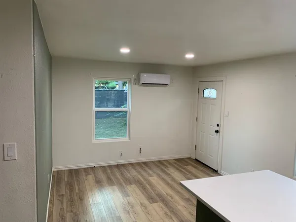 a view of a hallway to a room with wooden floor and a window