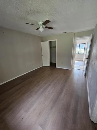 an empty room with wooden floor chandelier fan and windows