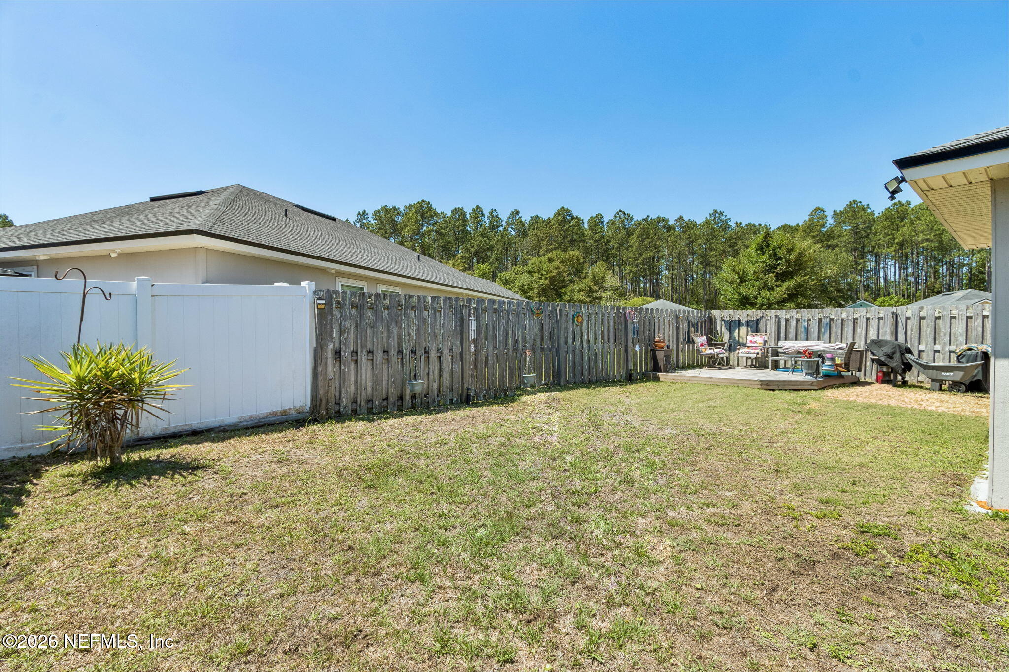 96034 Bass Lane Yulee, FL 32097 - Photo 46 of 50 a backyard of a house with table and chairs a barbeque and wooden fence