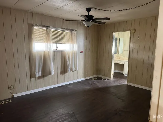 an empty room with wooden floor closet and windows