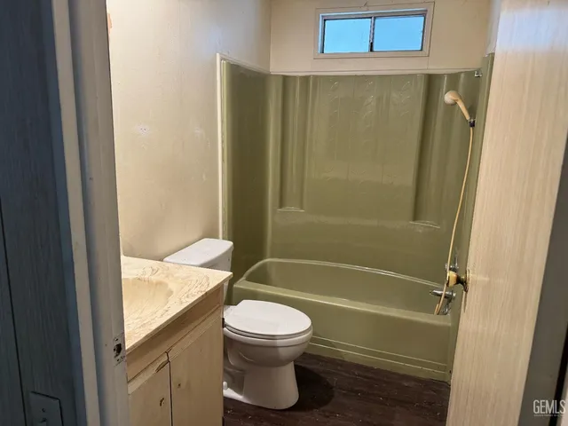 a bathroom with a granite countertop bathtub shower sink vanity and toilet