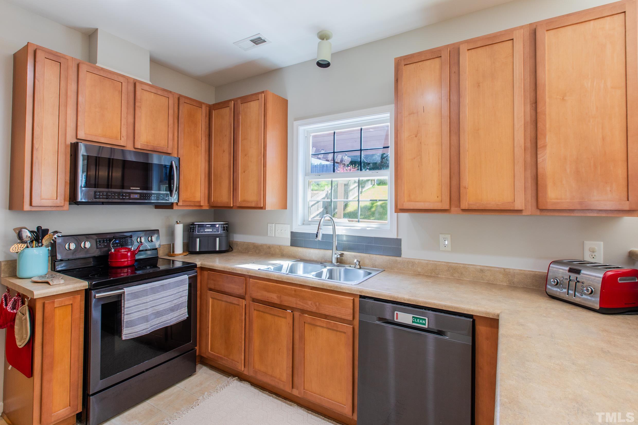 4228 Amber Stone Way Durham, NC 27704 - Photo 12 of 34 a kitchen with stainless steel appliances granite countertop white cabinets sink and window