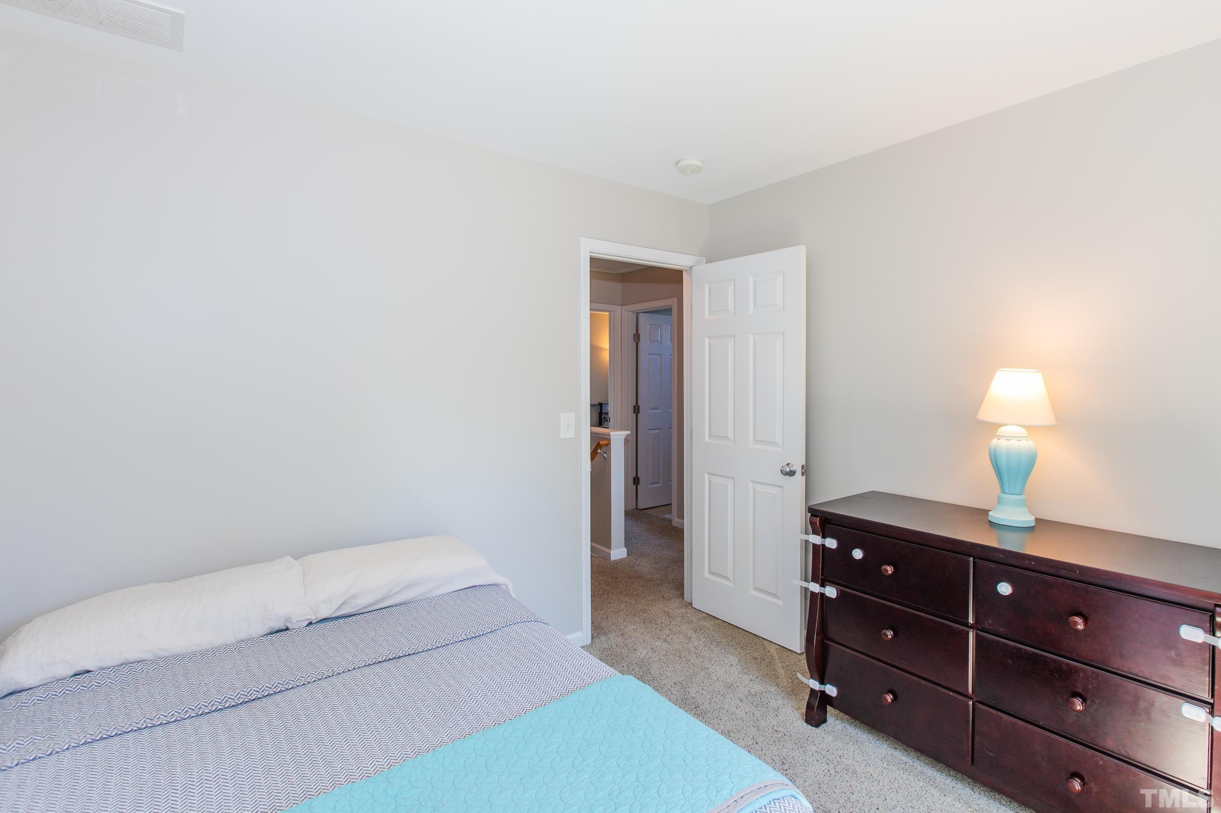 4228 Amber Stone Way Durham, NC 27704 - Photo 23 of 34 a bedroom with a bed and a lamp on dresser